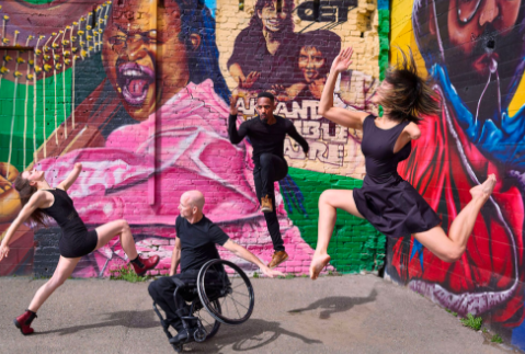 Four dancers in black clothes with colorful graffiti background